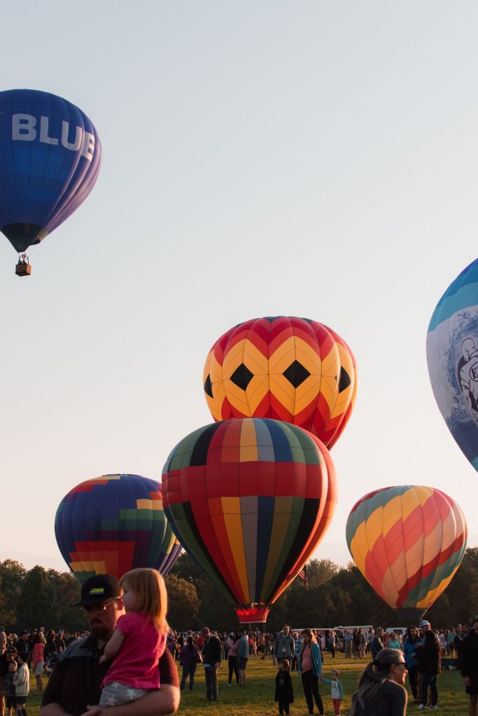 Colorful hot air balloons rising above a festival crowd