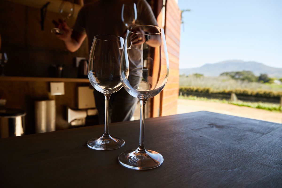 Wine glasses arranged at a vineyard with mountains in the distance